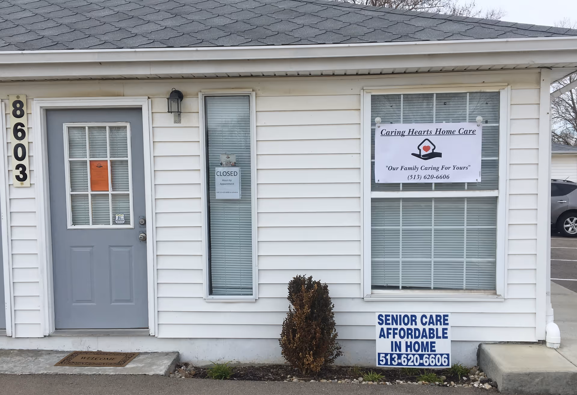 Front exterior of Caring Hearts Home Care building with banners and signs.