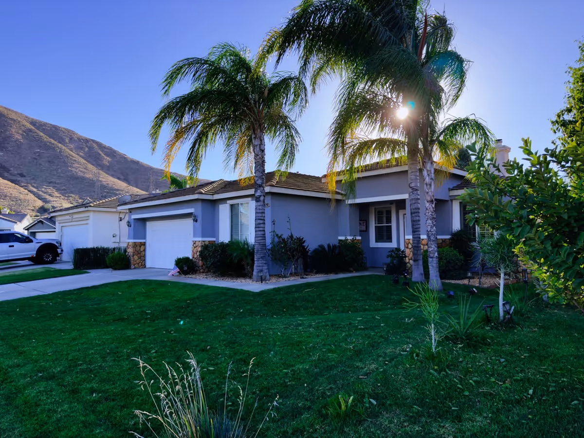 Front view of Magnolia Gardens senior facility with palm trees and green lawn.