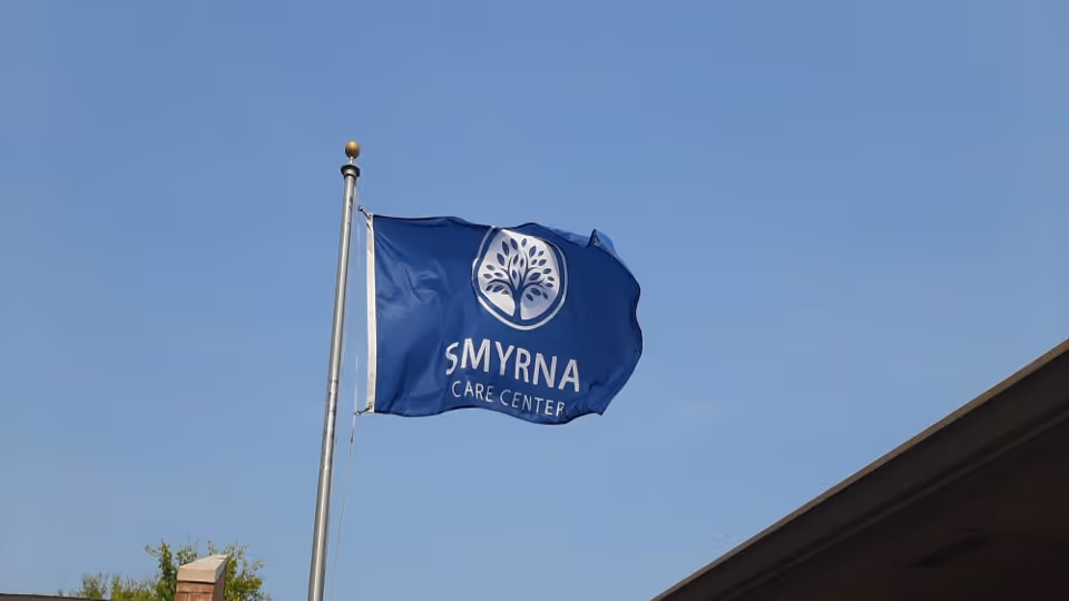 Blue Smyrna Care Center flag on a pole in front of a building