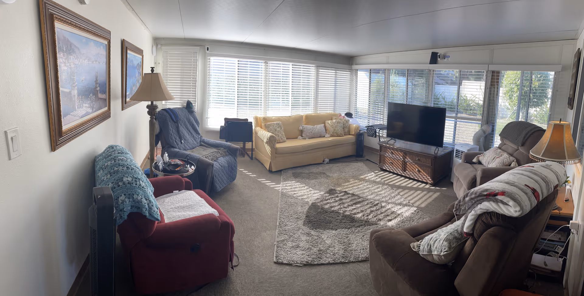 Cozy living room in Polly's Place with sofas, recliners, TV, and large windows.