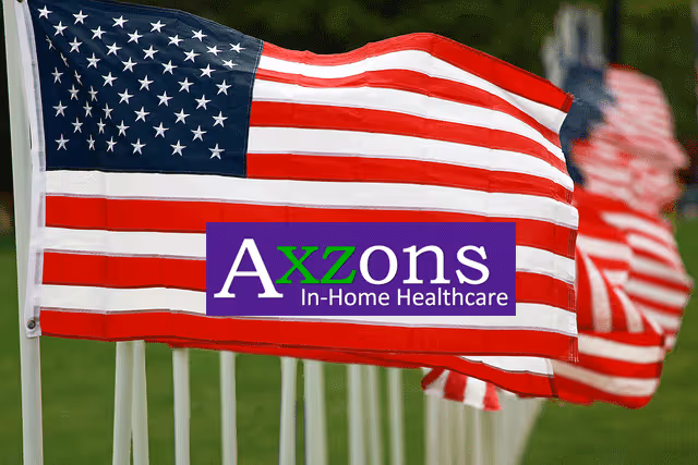 American flags wave beside an Axzons In-Home Healthcare sign outdoors.