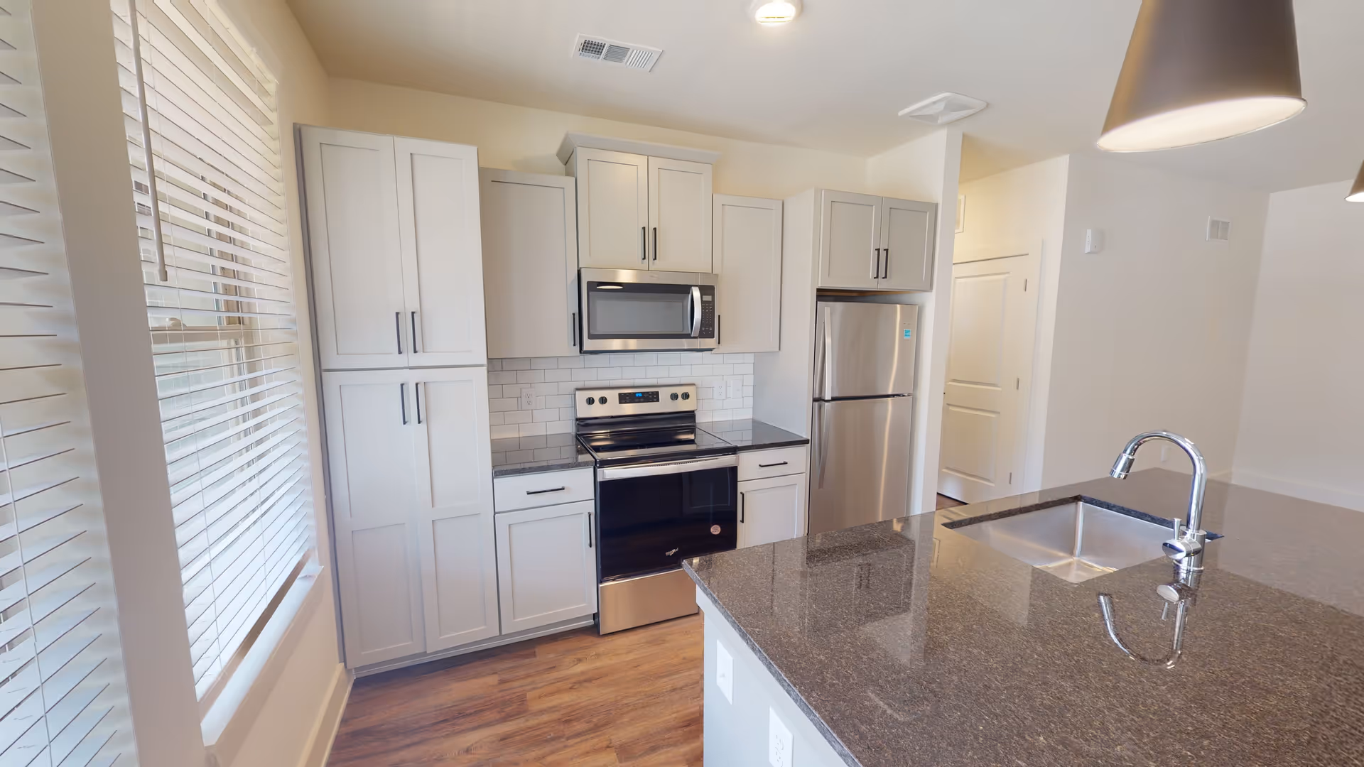 Modern kitchen with white cabinets, stainless steel appliances, and a granite island.