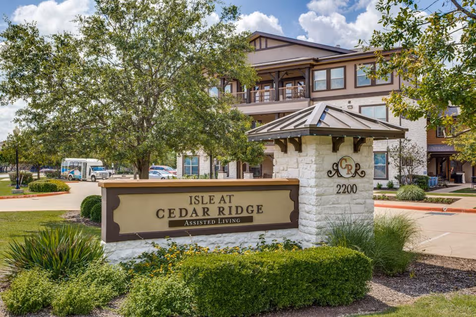 Exterior view of Isle at Cedar Ridge with entrance sign and landscaped grounds.