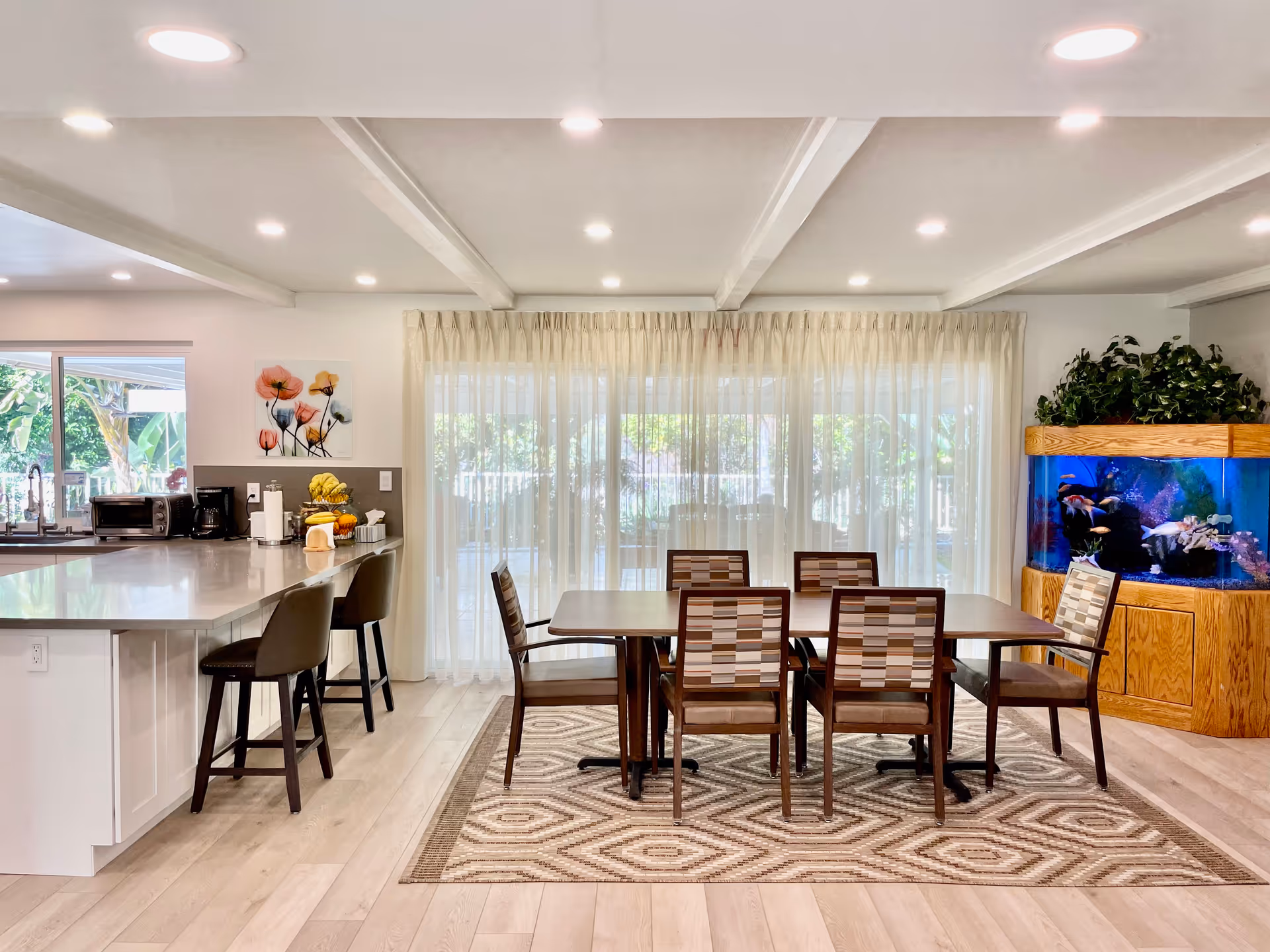 Bright dining area with a table, chairs, kitchen island, and fish tank.