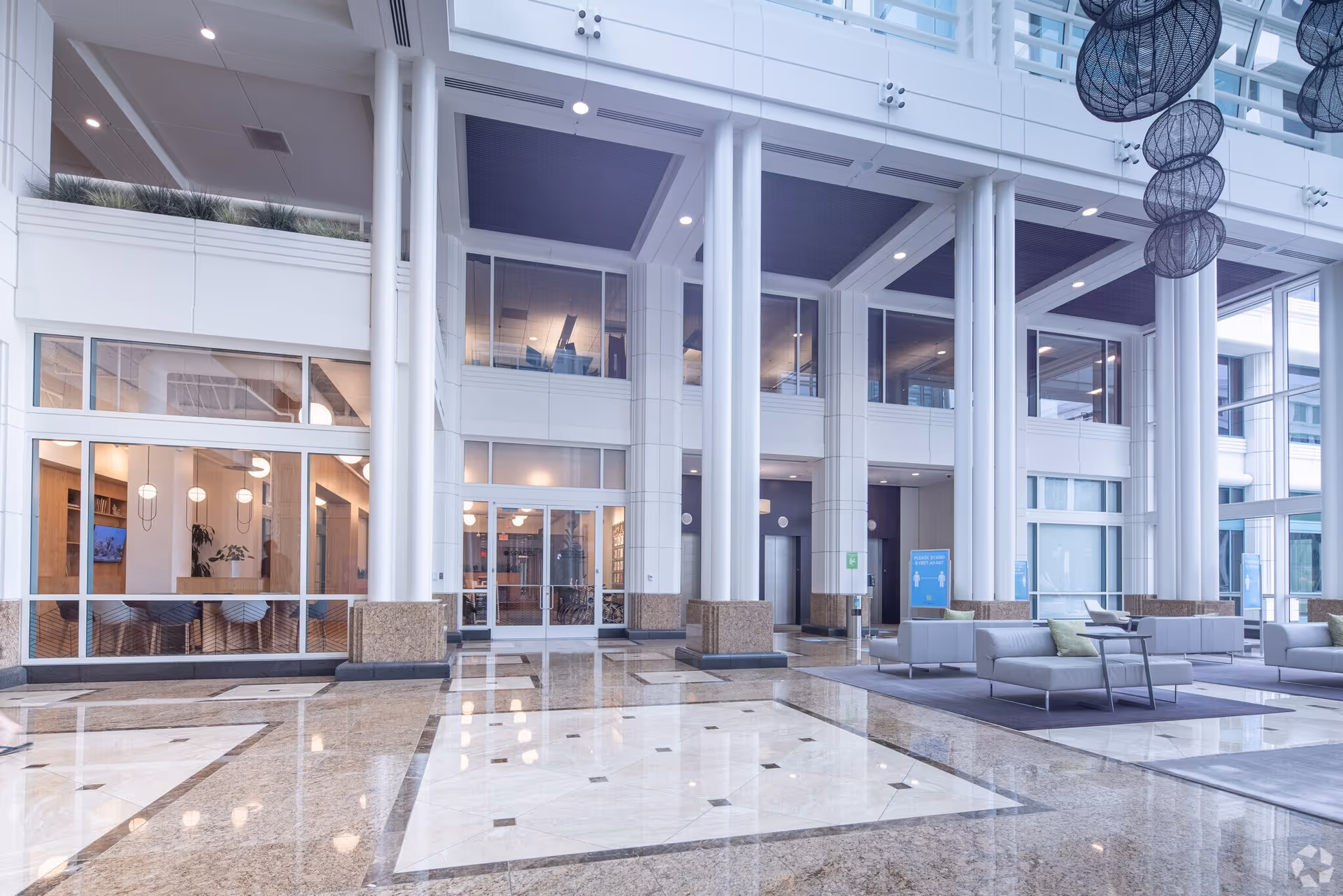Bright, spacious interior lobby with glass walls, seating areas, and polished floors.