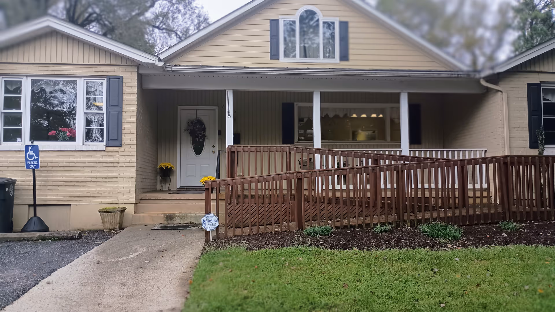 Exterior view of a beige senior living facility with a ramp and front porch.