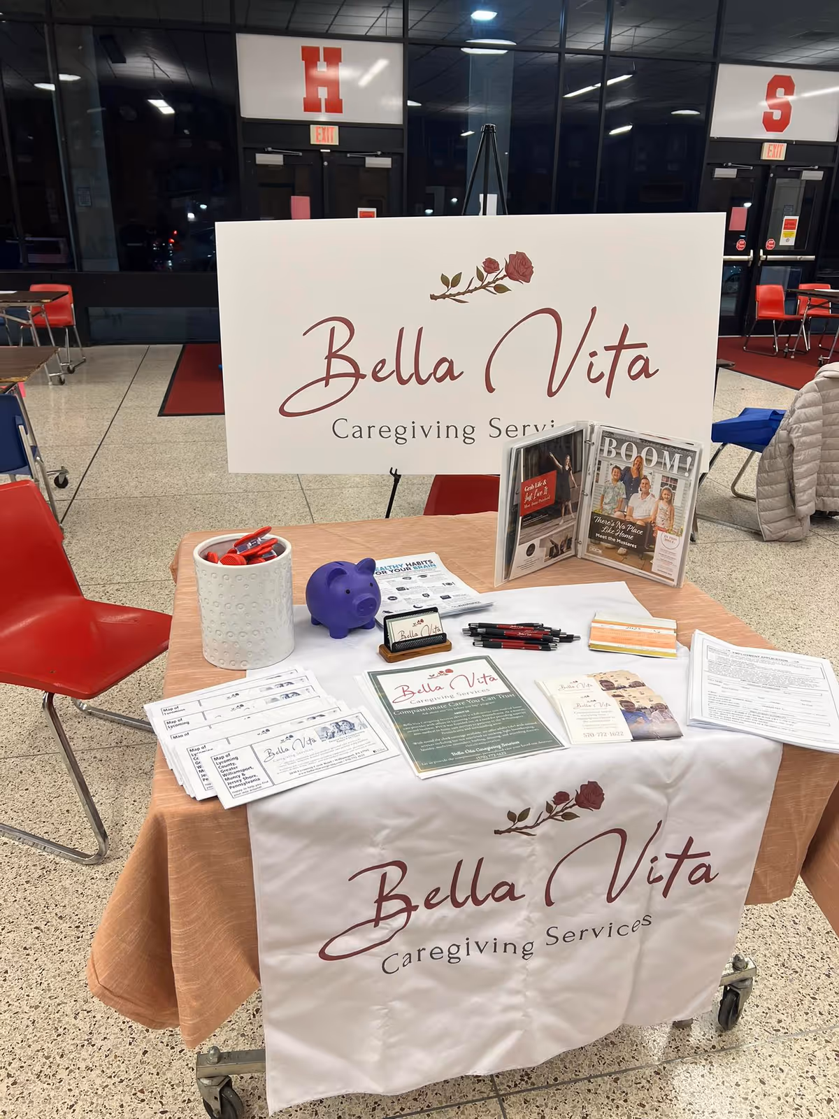 Indoor lobby booth with Bella Vita Caregiving Services signage and brochures.