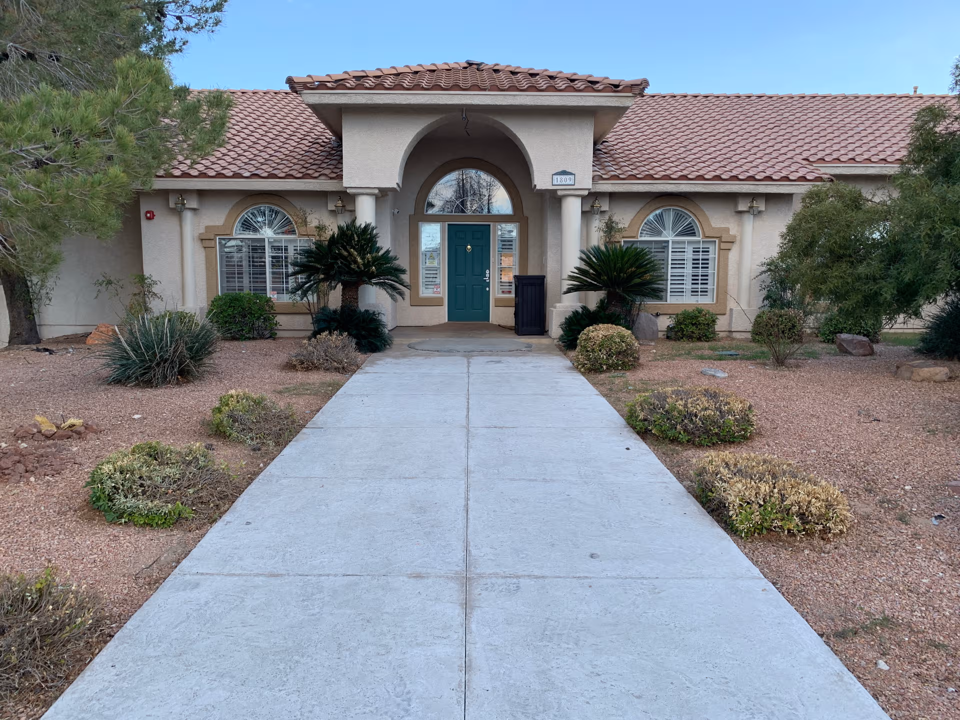 Front exterior of a single-story senior living building with arched entry and walkway.