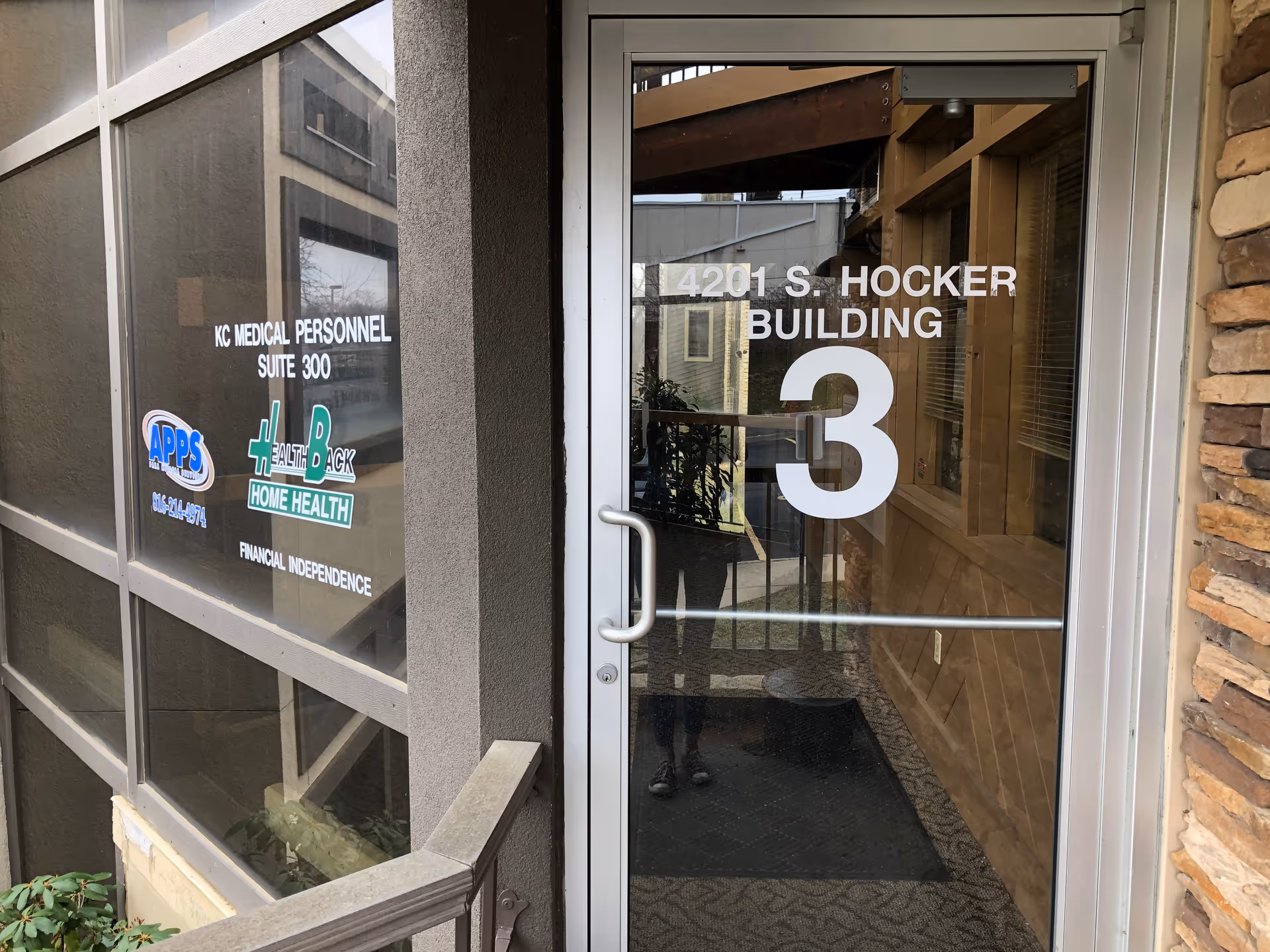 Glass entrance door displays the number 3 and the building address with facility logos nearby