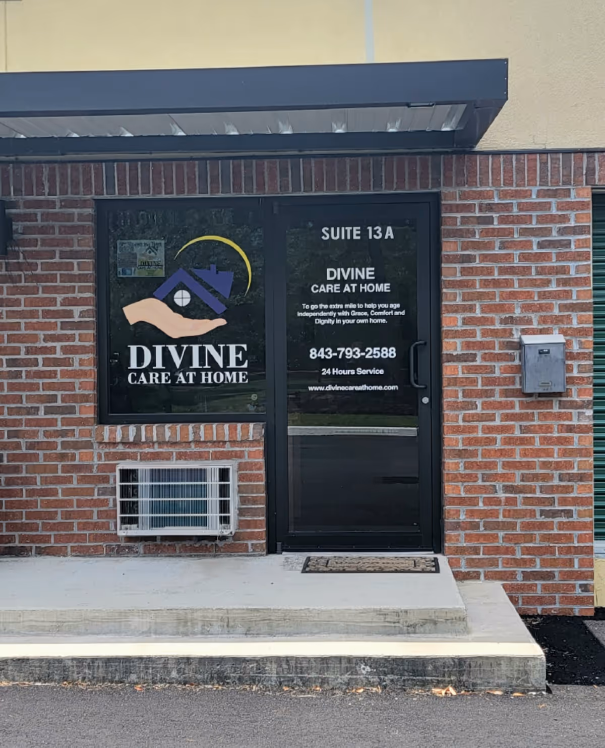 Brick exterior entrance with glass door displaying Divine Care at Home and Suite 13A.