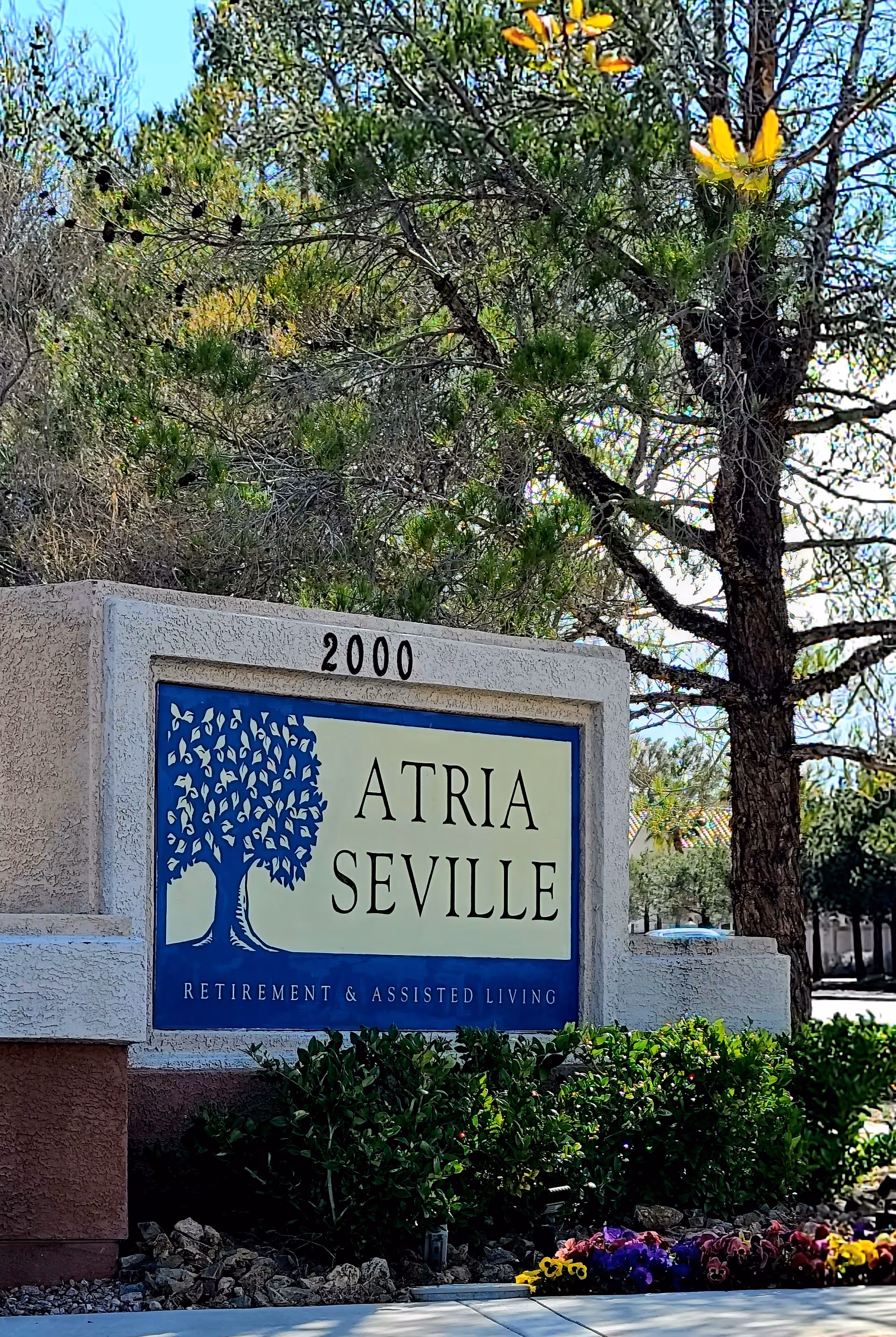Atria Seville retirement and assisted living sign with trees and flowers.