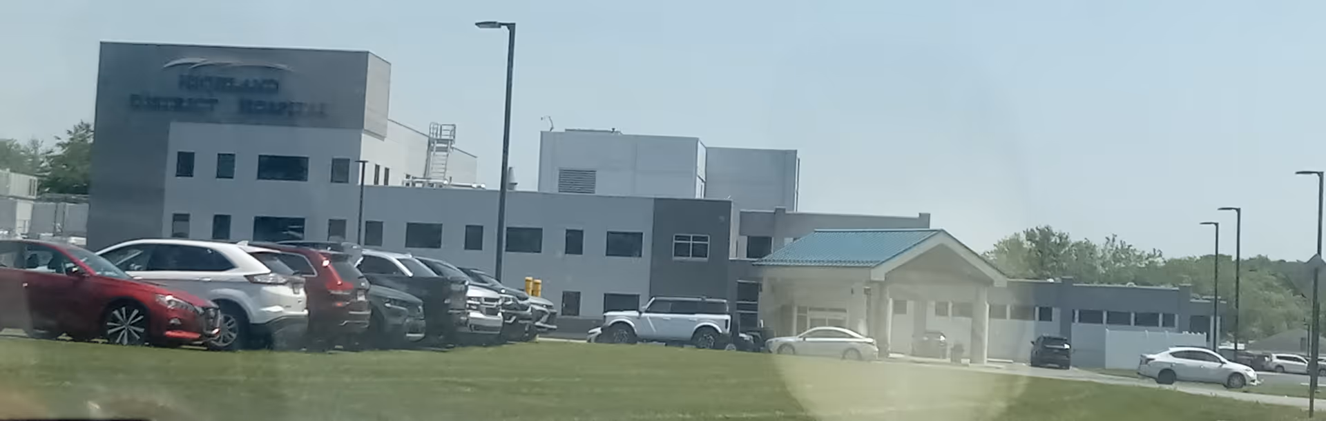 Exterior view of Highland District Hospital with cars in a parking lot