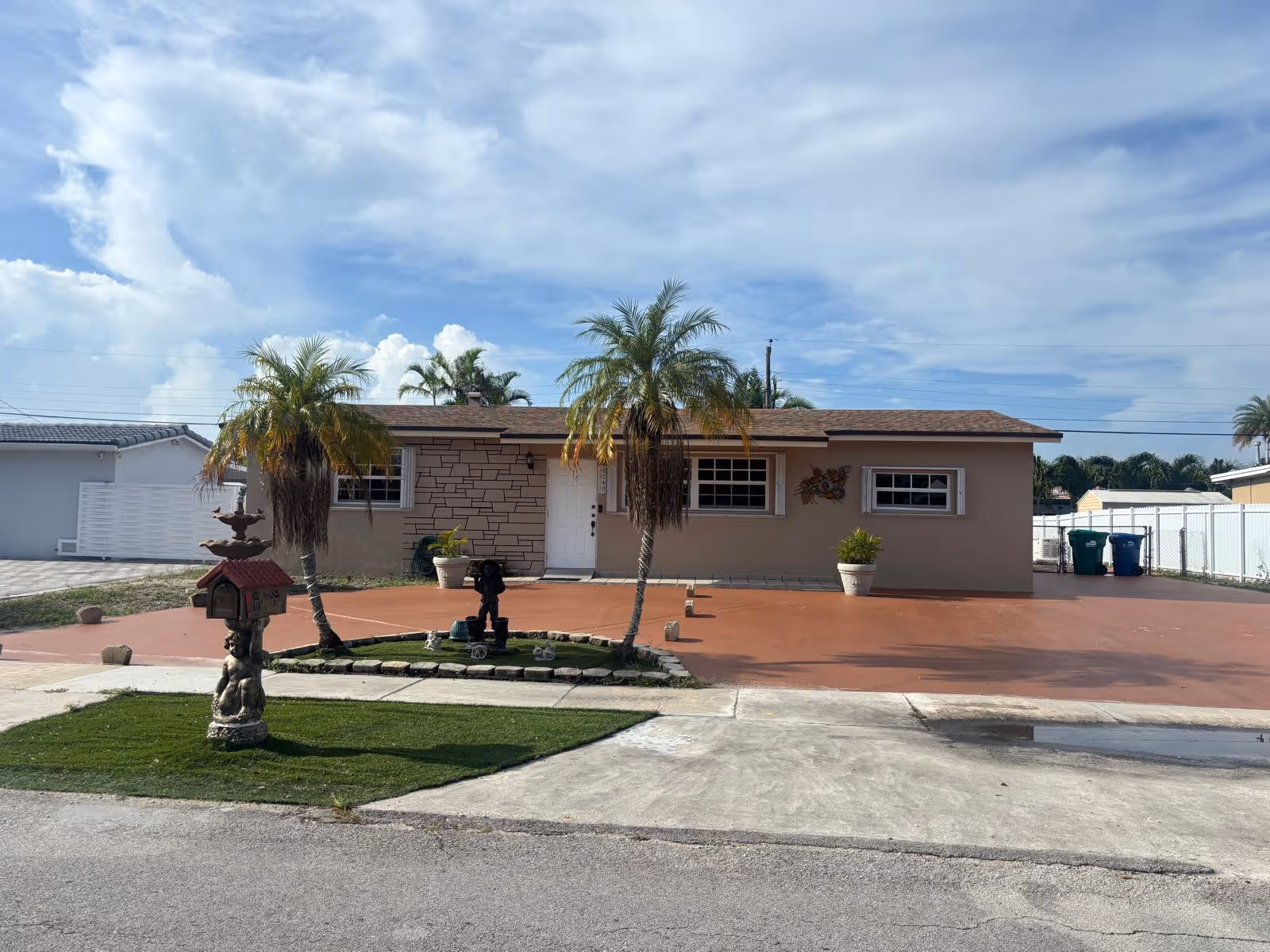 A single-story beige facility with palm trees, a red driveway, and a small front yard fountain.