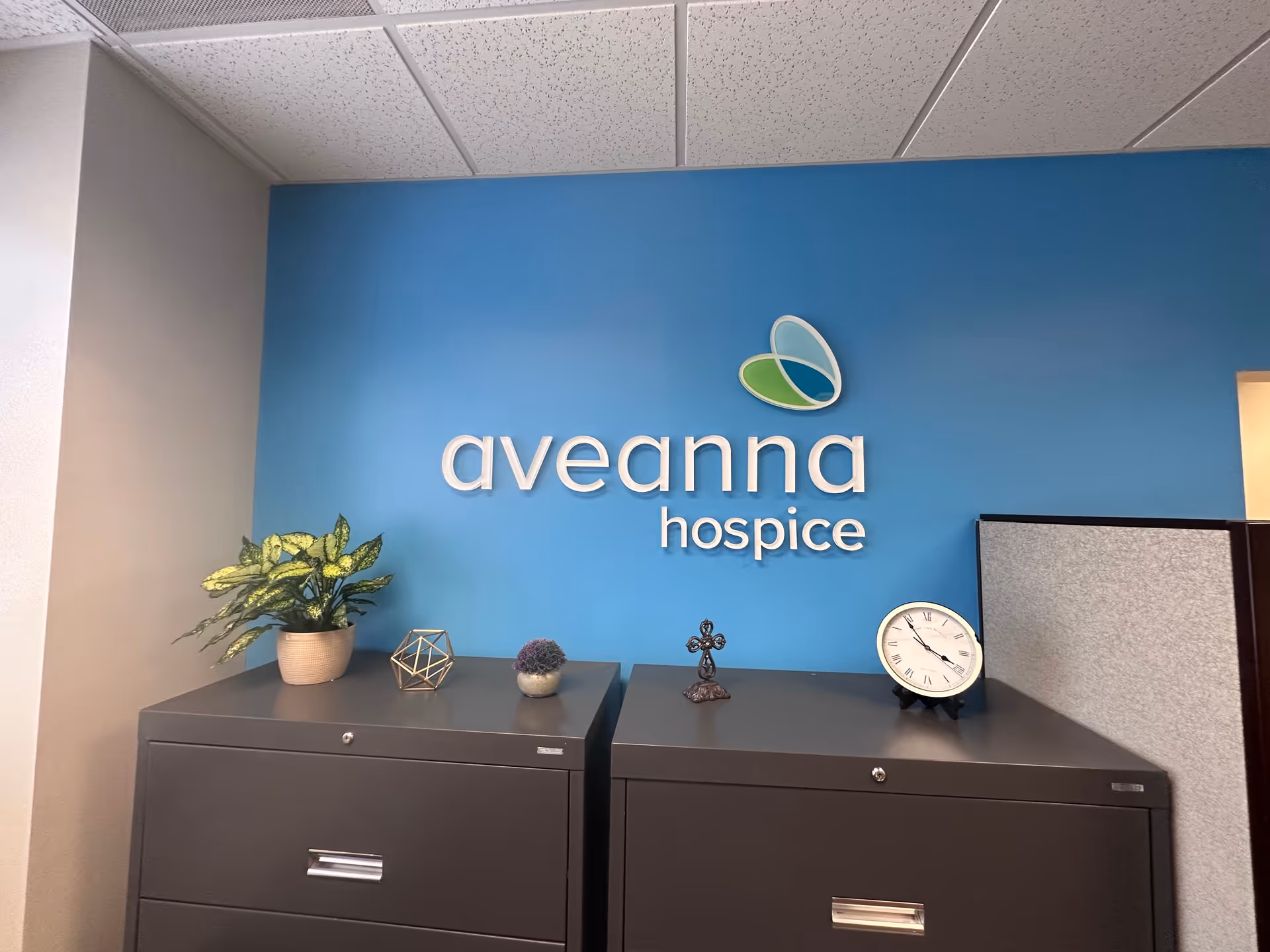 Reception area with blue wall displaying Aveanna Hospice logo and office cabinets.
