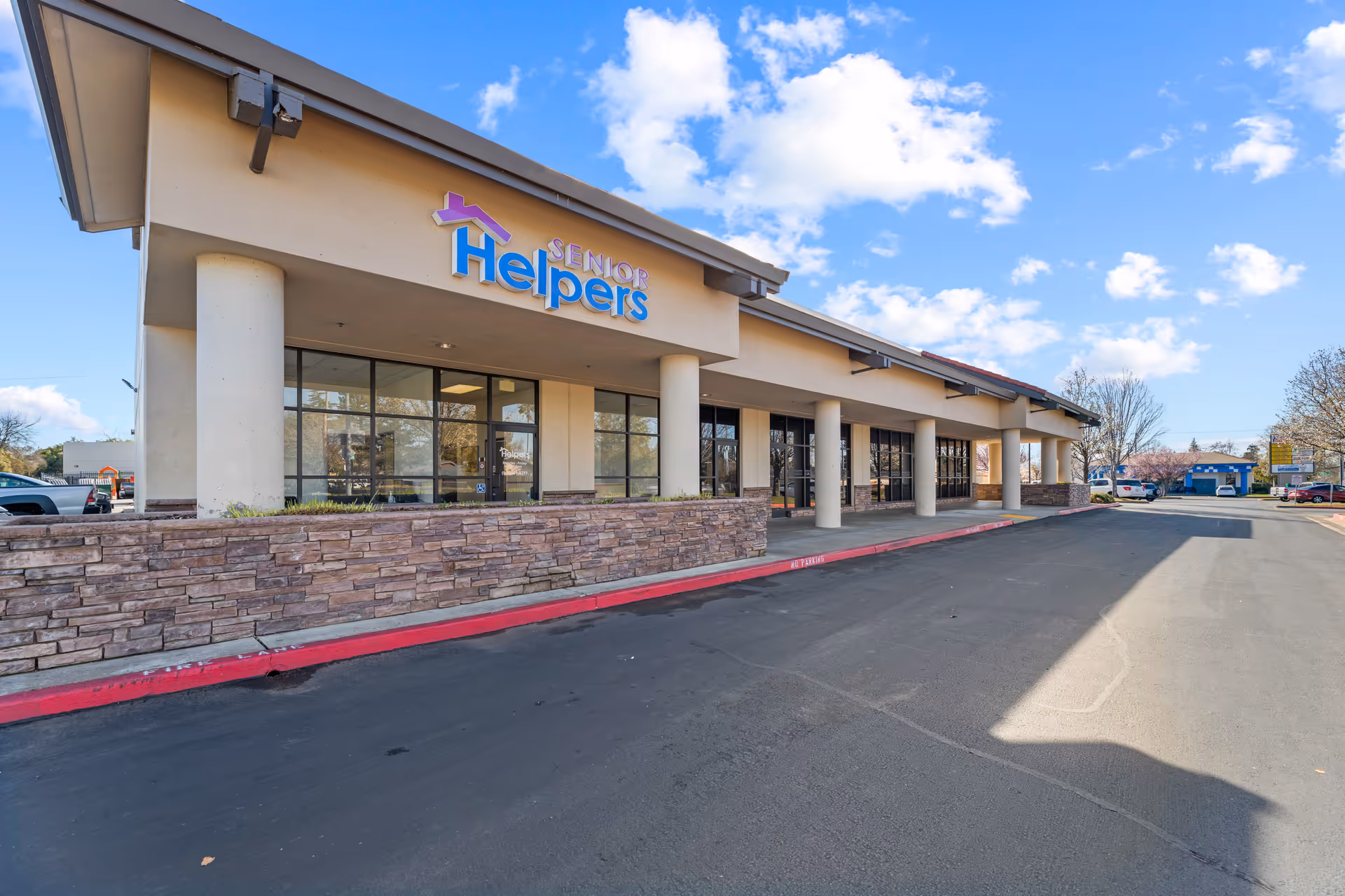 Exterior view of a Senior Helpers senior care facility with large windows and parking.
