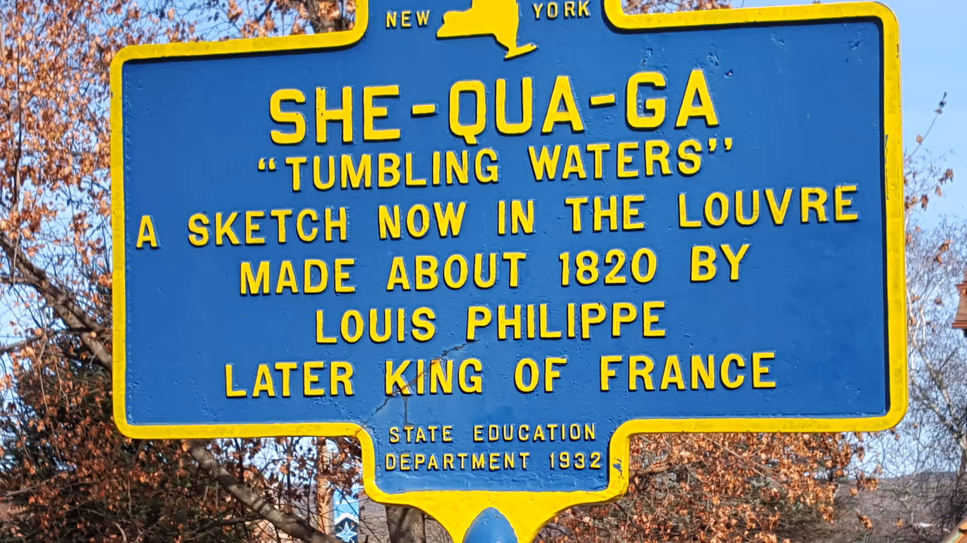 Blue roadside signboard with yellow lettering detailing a historical artwork and its creator.
