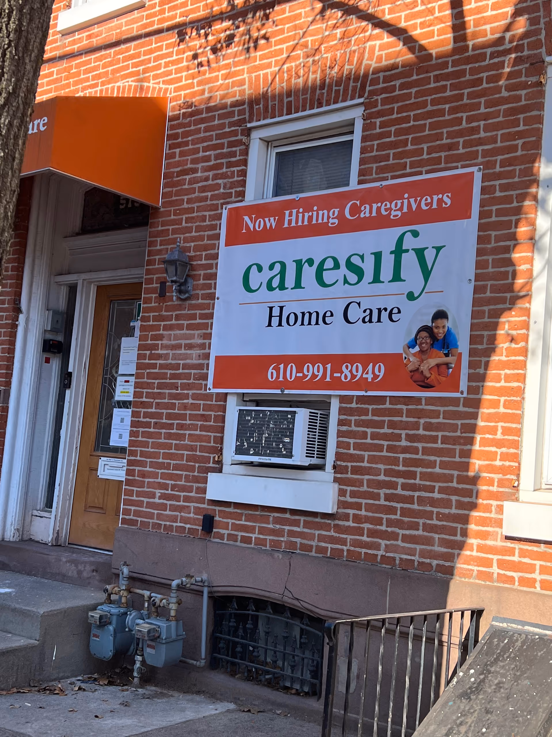Brick building exterior with a large Caresify Home Care sign and window air conditioner.