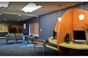 Interior lounge with curved wooden desk, computer workstations, blue walls, and seating area.