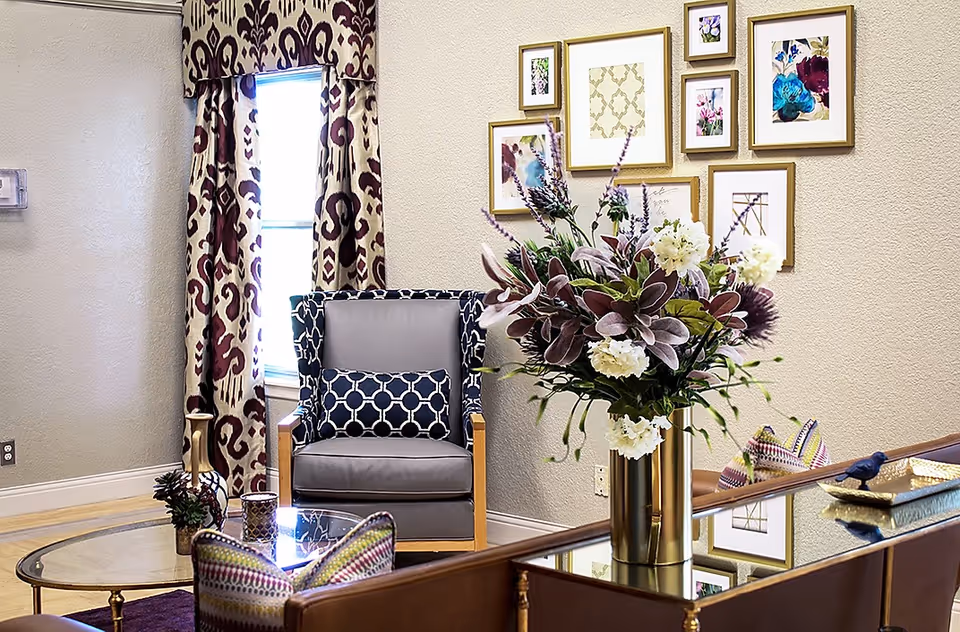 A stylish seating area with a chair, glass coffee table, and floral arrangement.