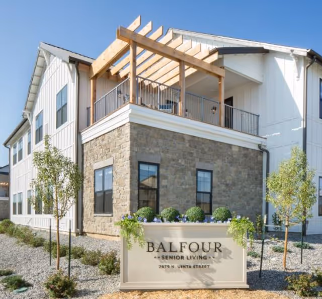 Front exterior of Balfour Central Park senior living facility with stone base and balcony.