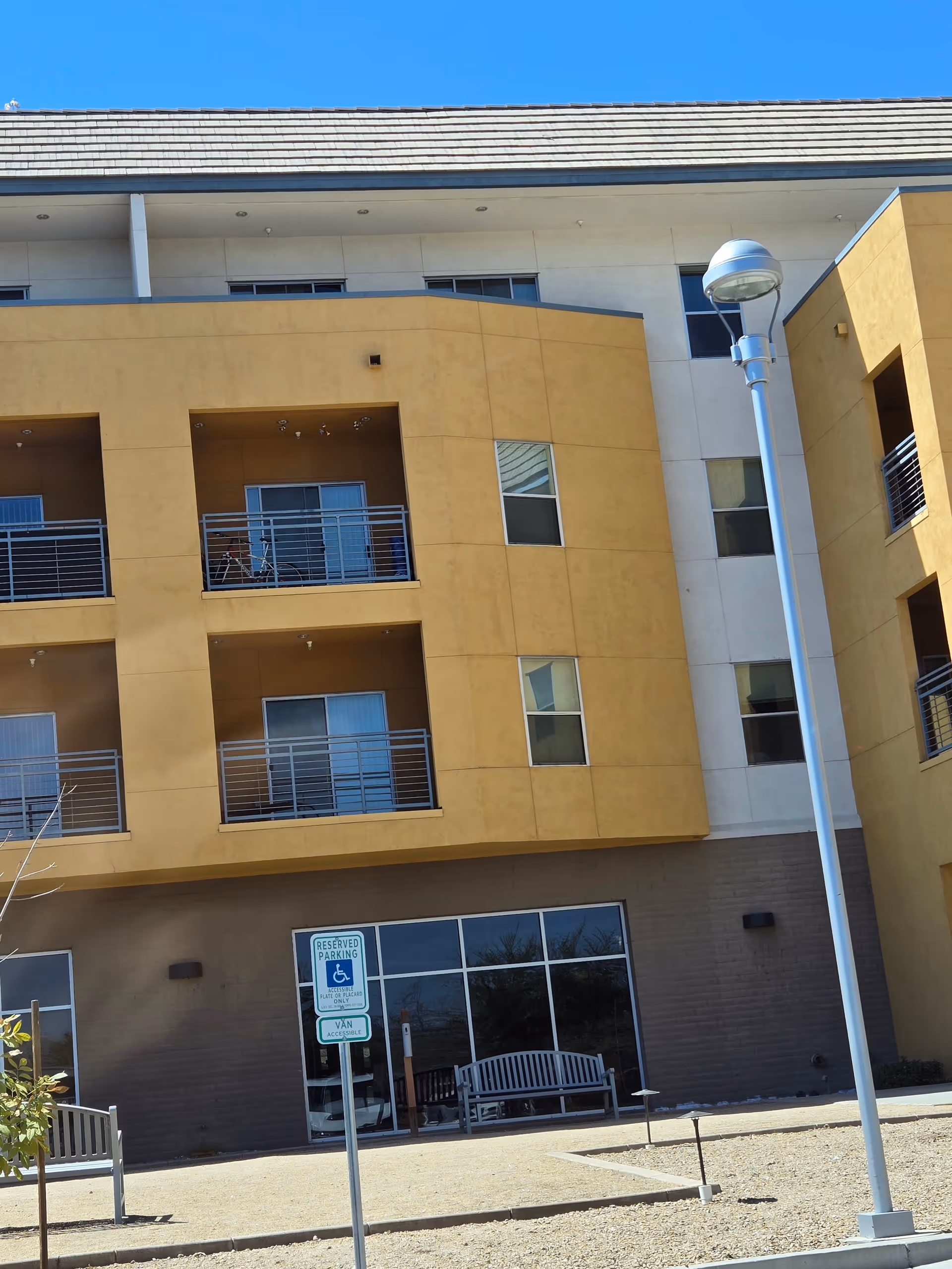 Exterior view of Apache ASL Trails building with balconies, bench, and streetlamp.
