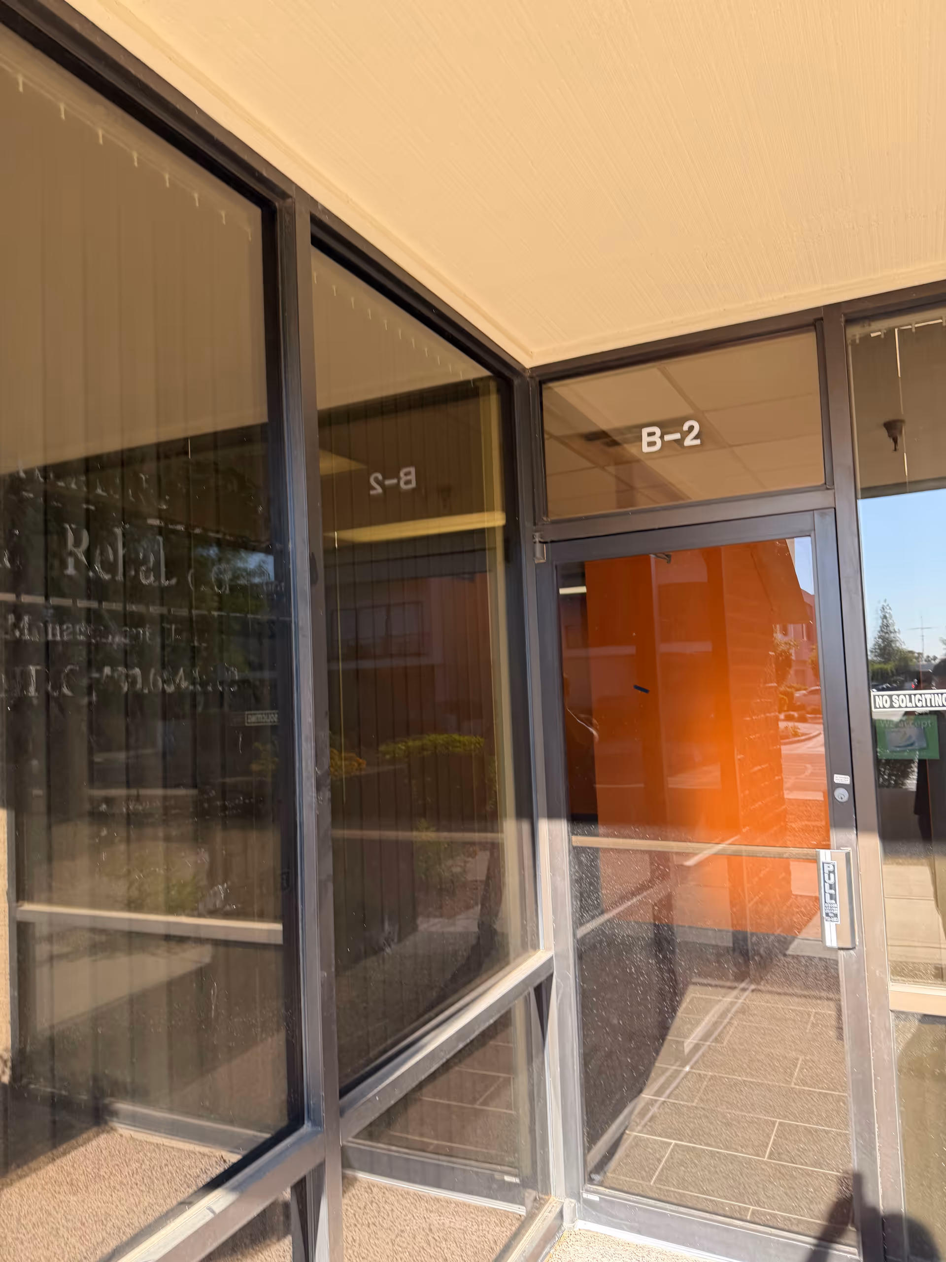 Glass storefront entrance with dark metal frames and an orange column labeled B-2.