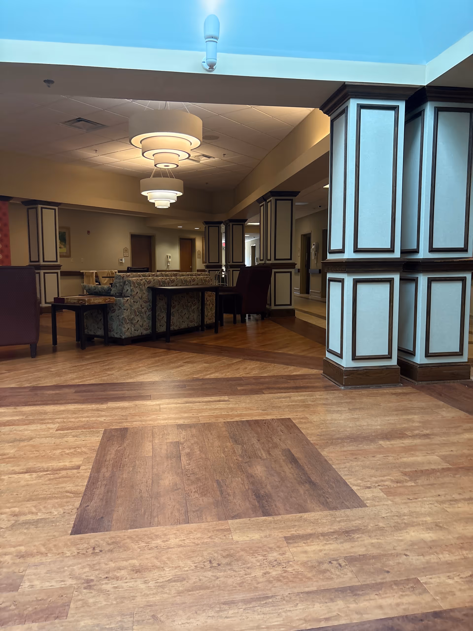 Interior lounge-style common area with wood floors, seating, and decorative columns.