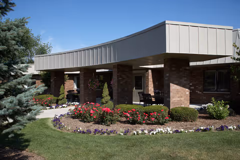 Exterior view of Medilodge of Portage entrance with brick columns and landscaped garden beds.