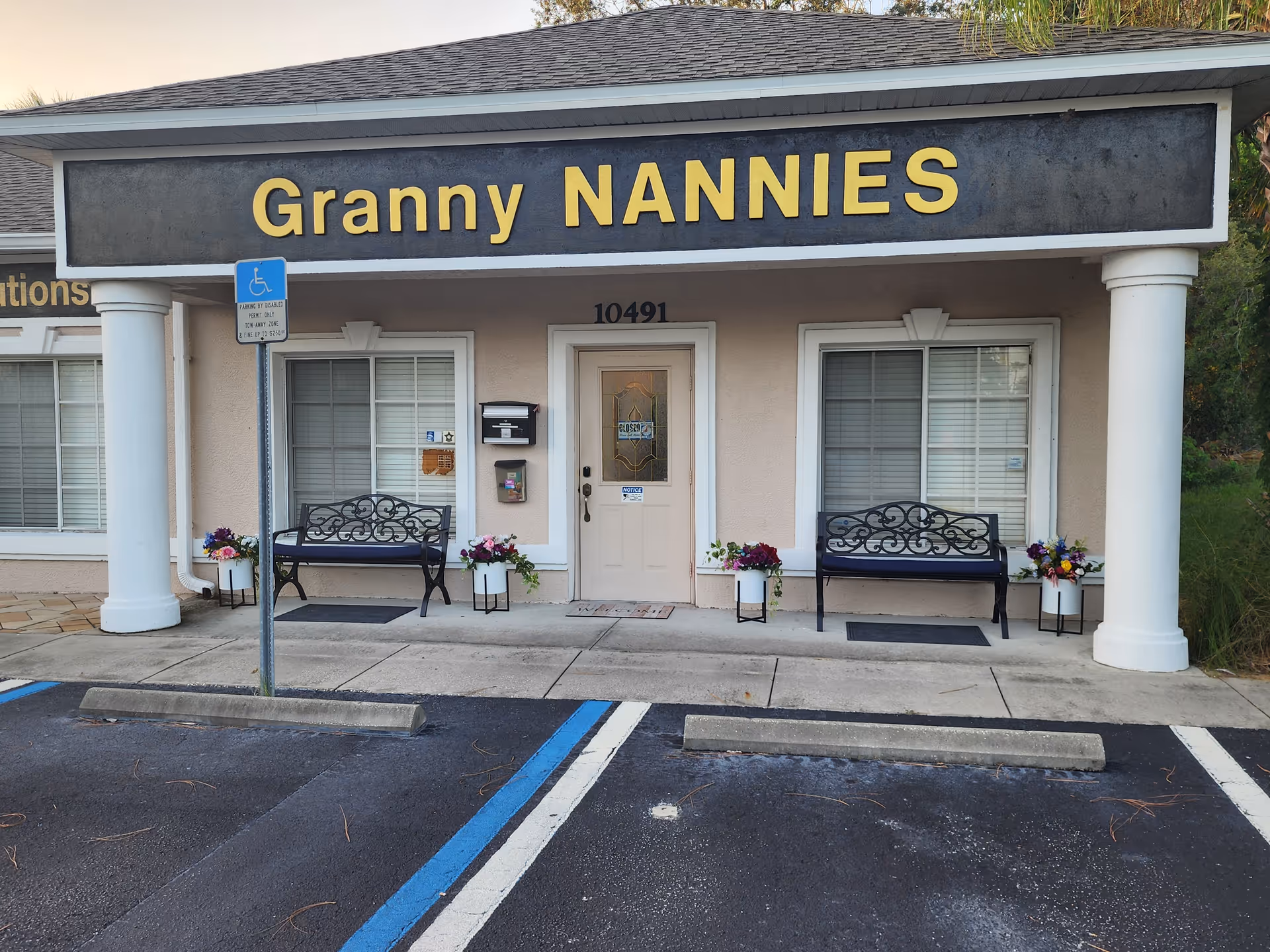 Front of Granny NANNIES Senior Care with benches, planters, and handicap parking sign.