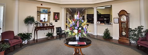 Elegant lobby of a senior living community with floral centerpiece, seating, and classic furnishings.