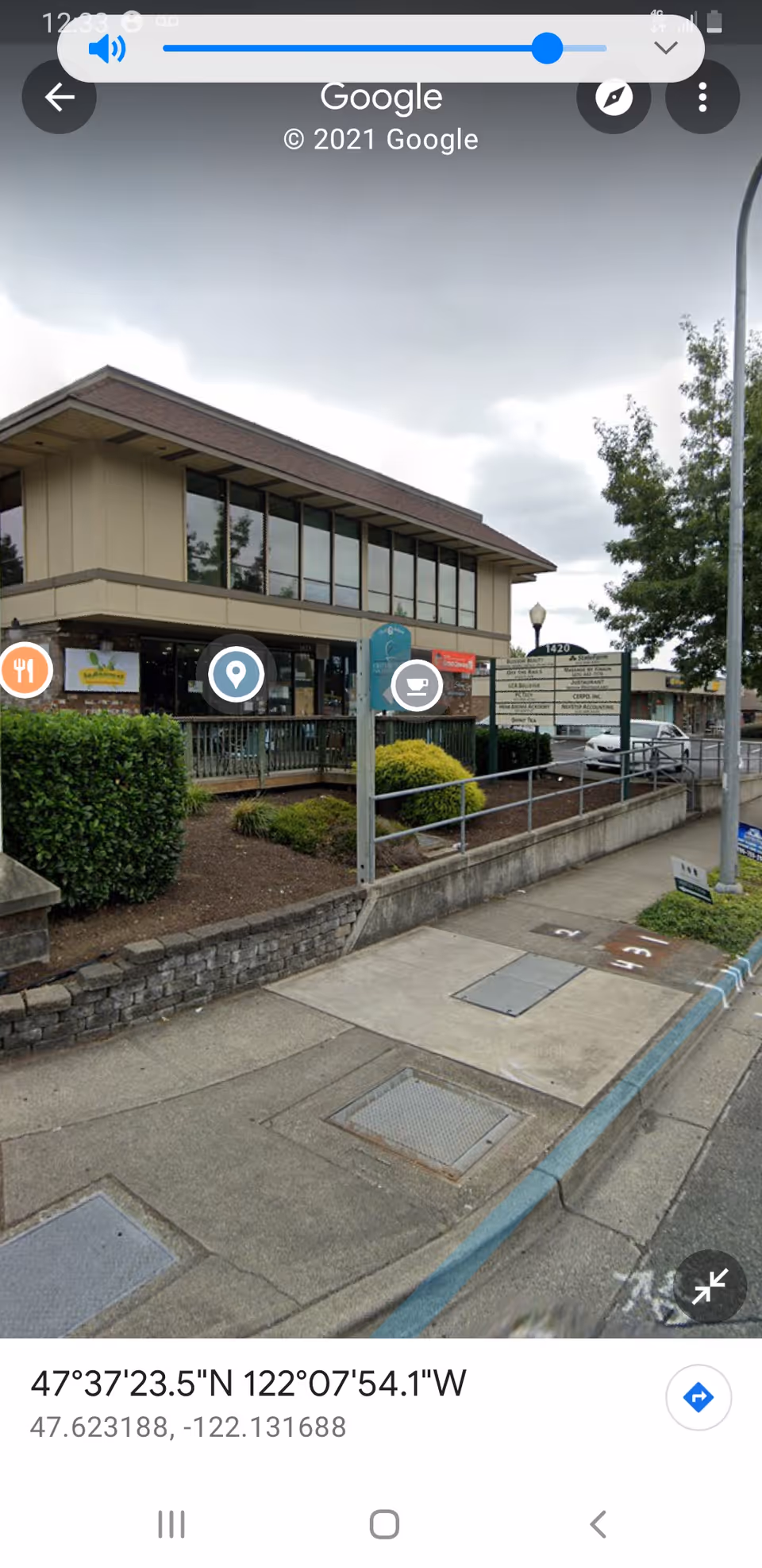 Exterior view of a storefront-style building with sidewalk, landscaping, and parking.