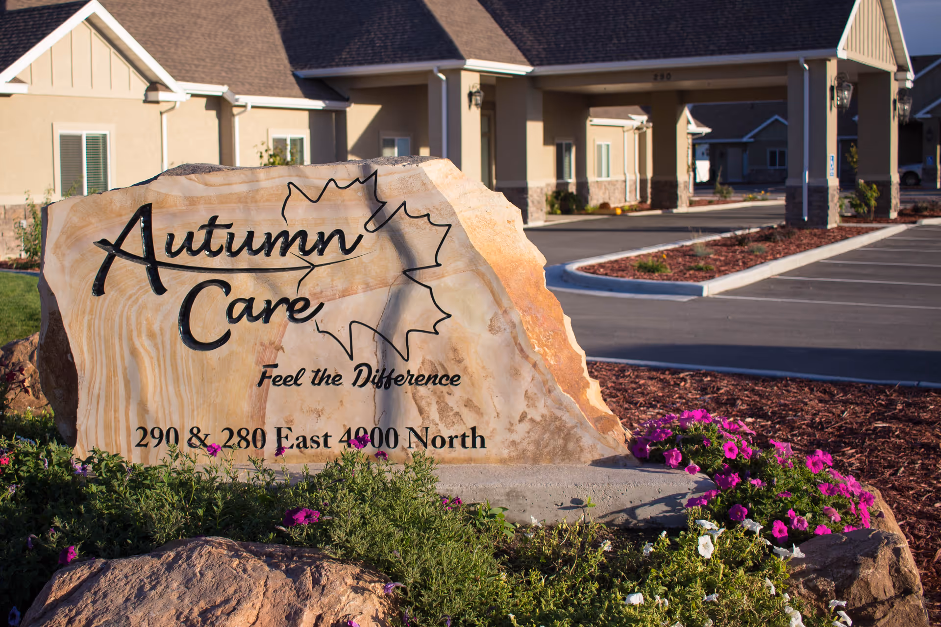 A large rock sign reading Autumn Care Living Center at the entrance of a facility