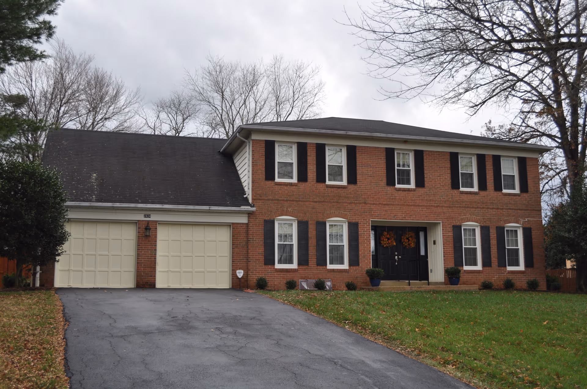 Brick two-story building with a two-car garage, driveway, and front lawn.