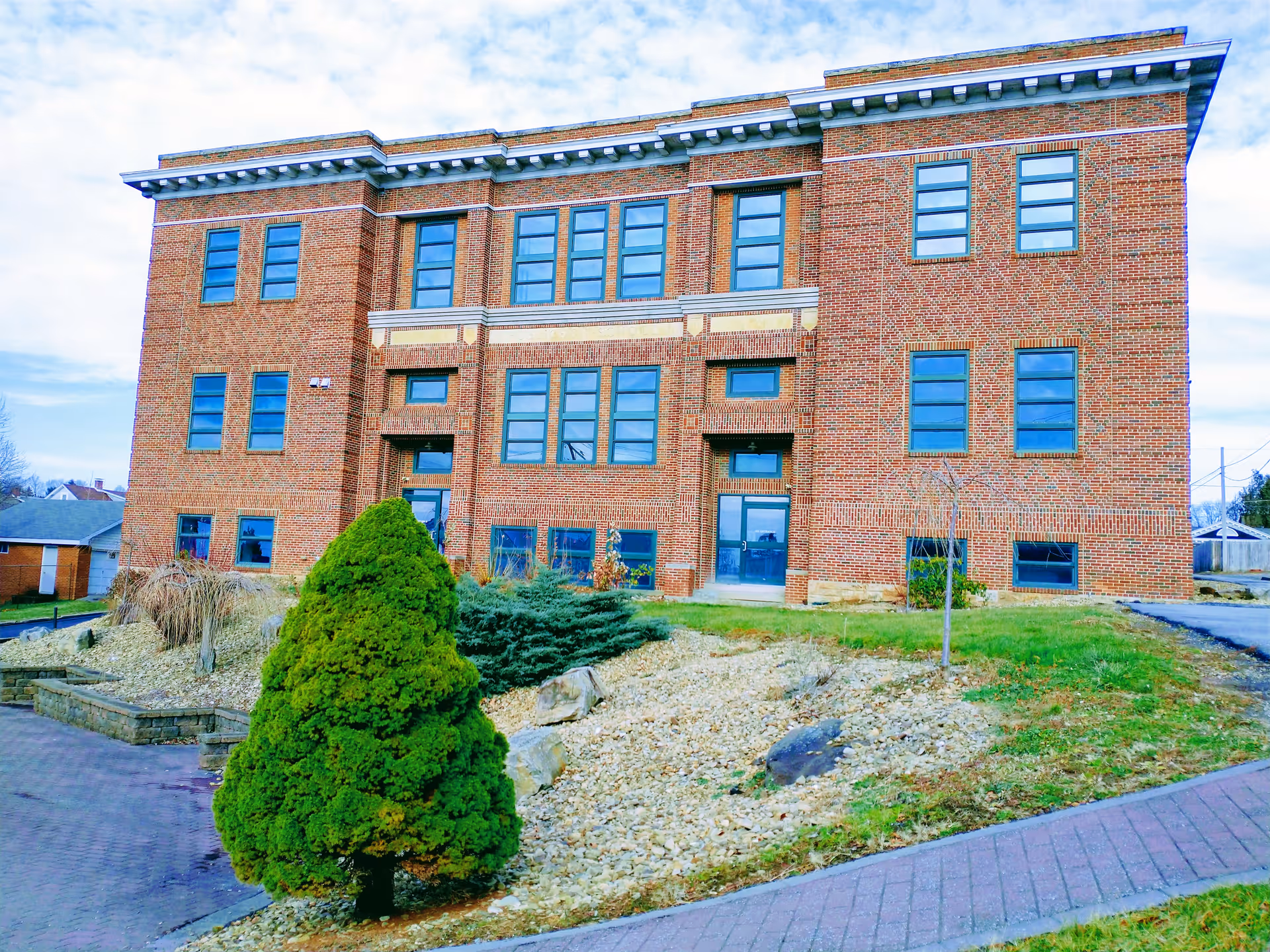 Brick three-story facility building with multiple windows and a landscaped front yard