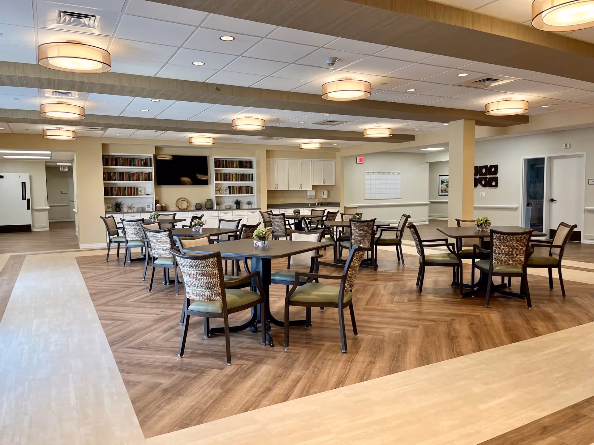 Spacious senior living dining area with round tables, chairs, and built-in cabinets.