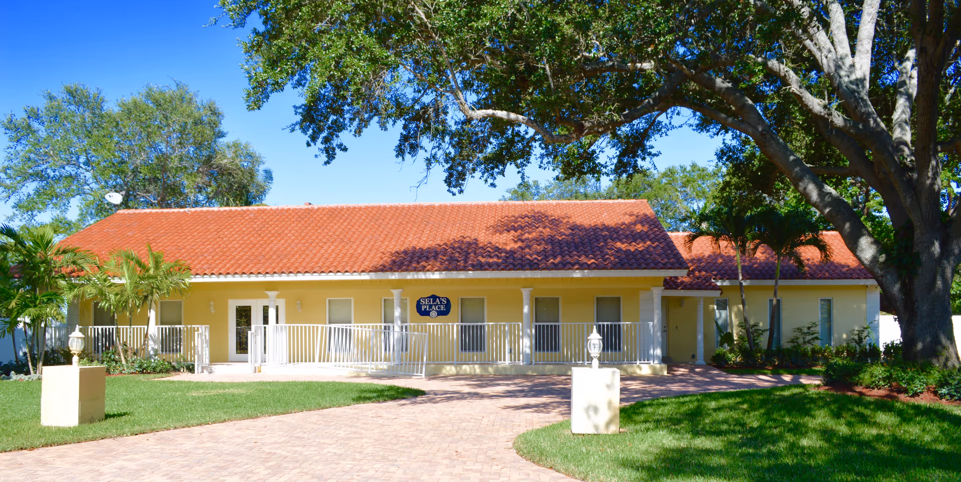 Front view of a single-story yellow facility with a red-tiled roof and white railings.