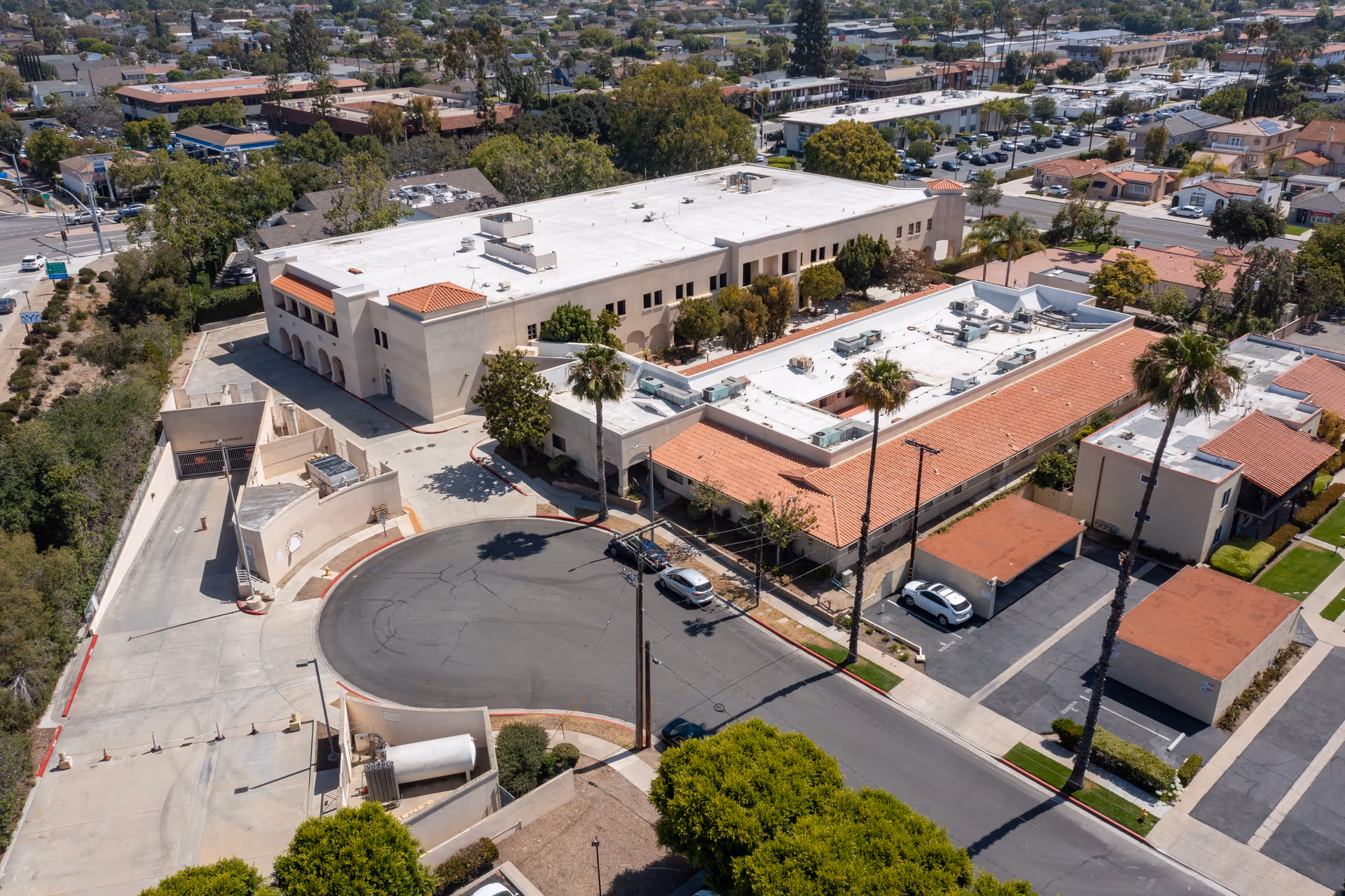 Aerial view of Tustin Healthcare Center complex with white buildings and palm trees.
