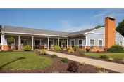 Single-story facility with a covered front porch, brick chimney, and well-maintained landscaping.