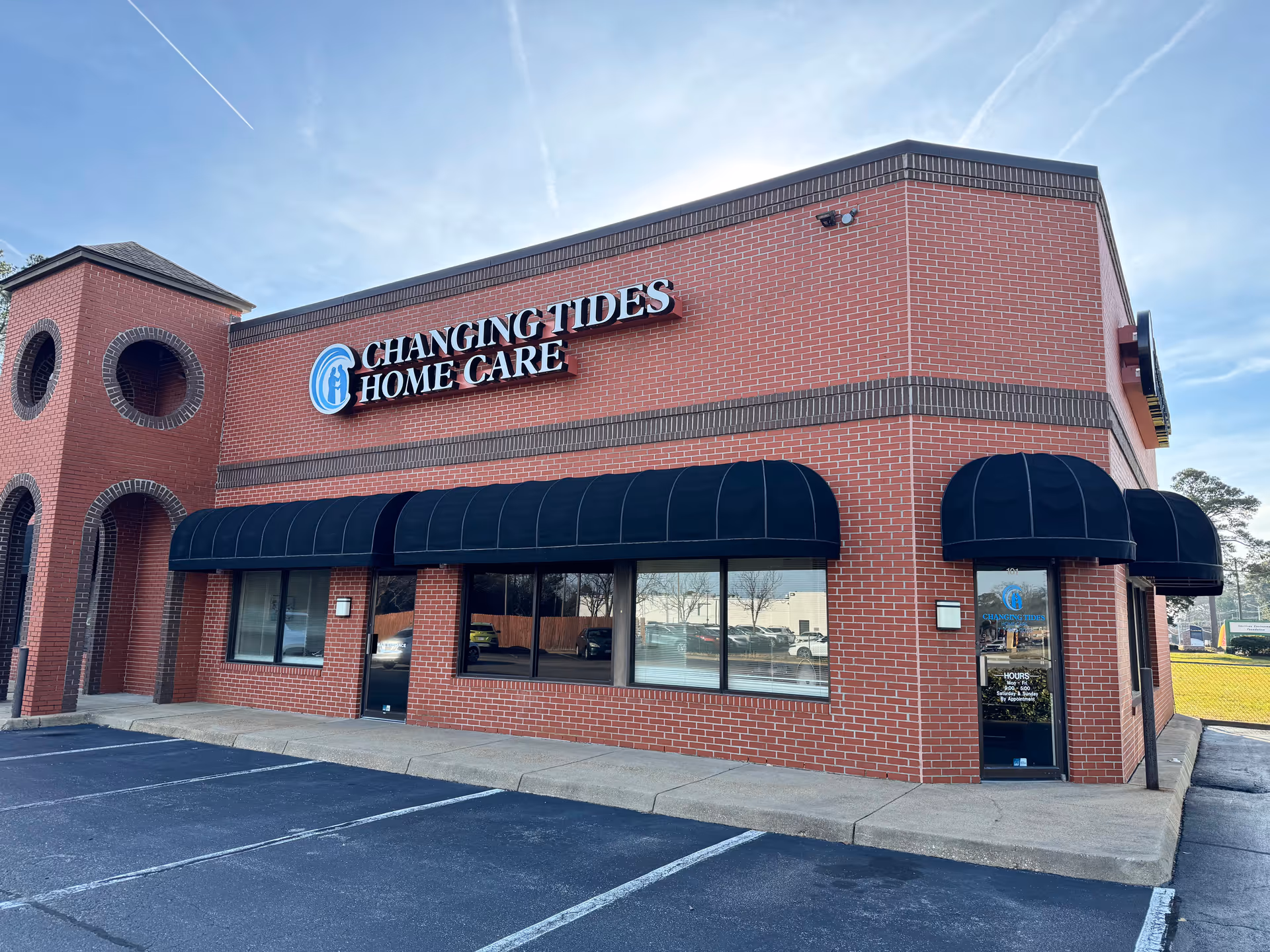 Brick building with Changing Tides Home Care sign; blue awnings and storefront windows.