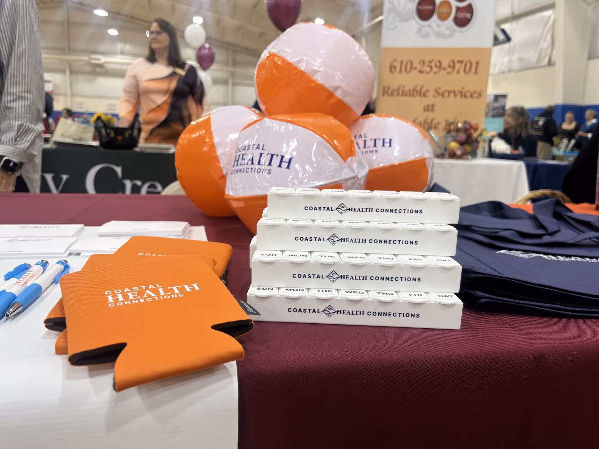 Coastal Health Connections booth with branded boxes, swag, and balloons at an indoor expo.