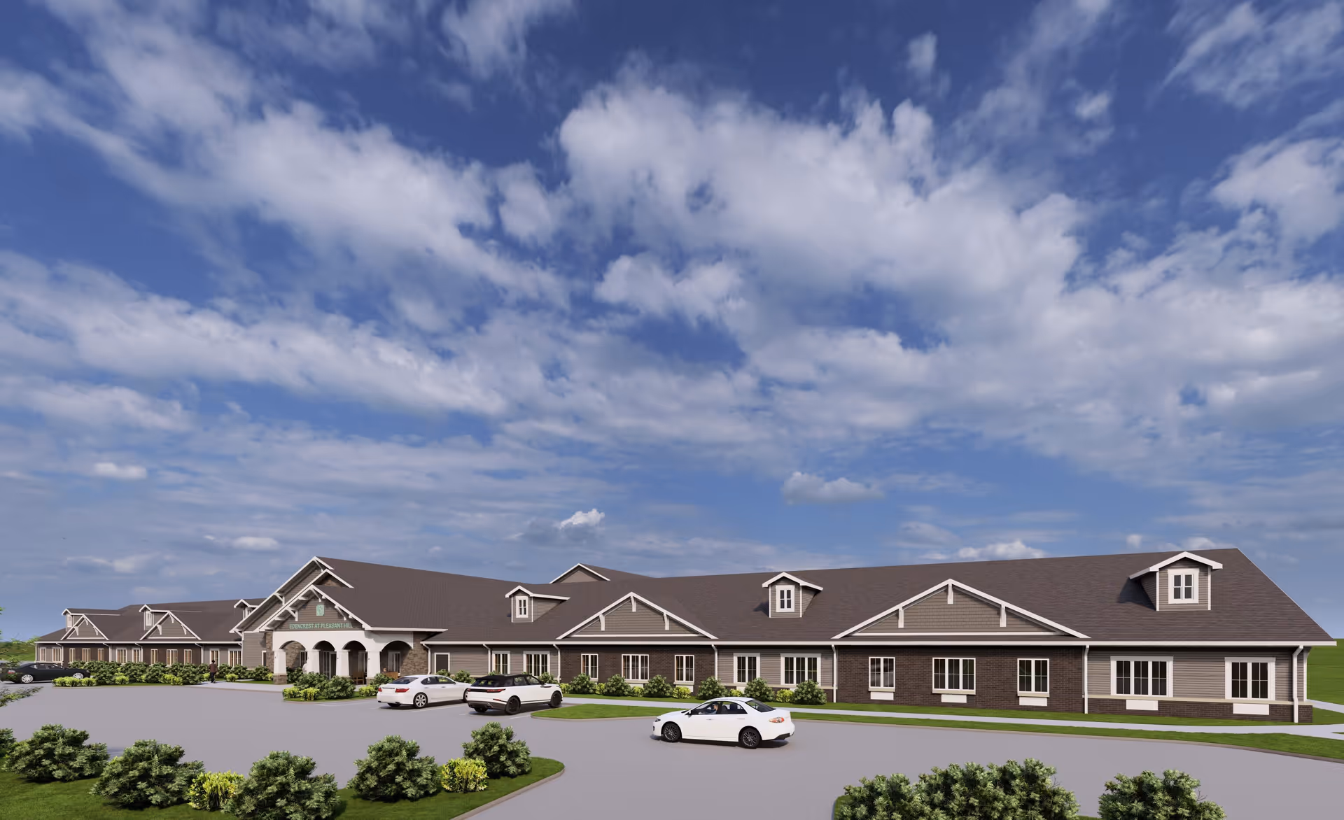 Exterior view of a single-story senior living facility building named Edencrest at Pleasant Hill under a partly cloudy blue sky, with a driveway and several parked cars in front, surrounded by green shrubs and grass.
