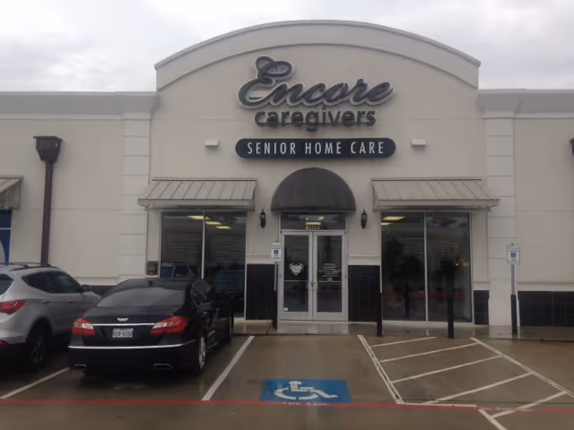 Front exterior of Encore Caregivers senior home care facility with glass doors and parking.