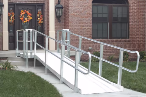 Wheelchair ramp and brick facility entrance with wreaths on doors.