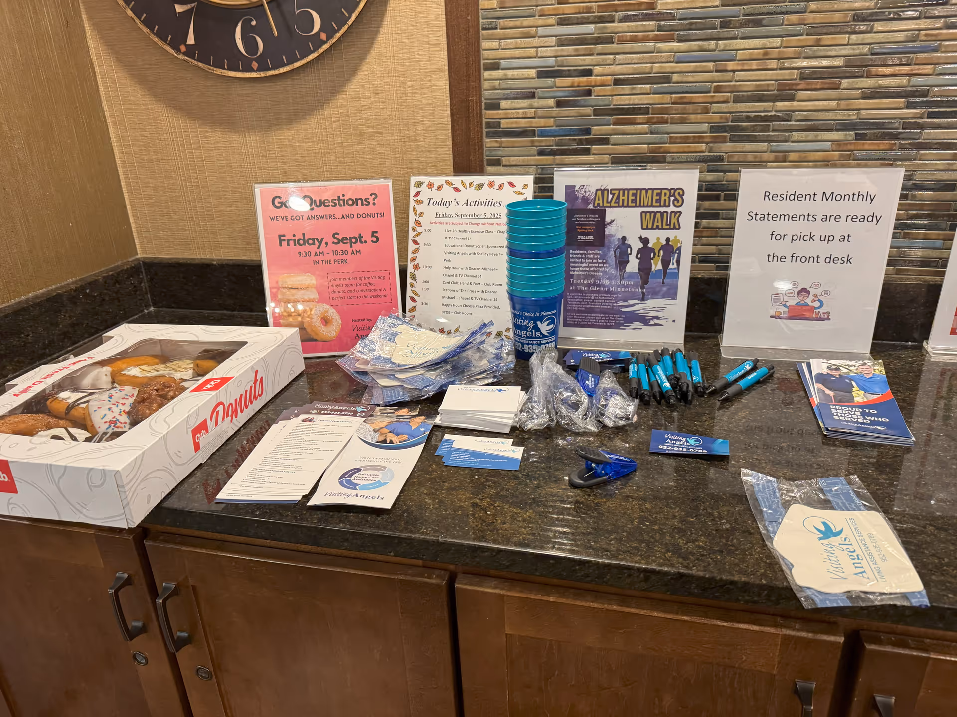 Lobby counter in senior care facility with donuts, flyers, pens, and front desk signage