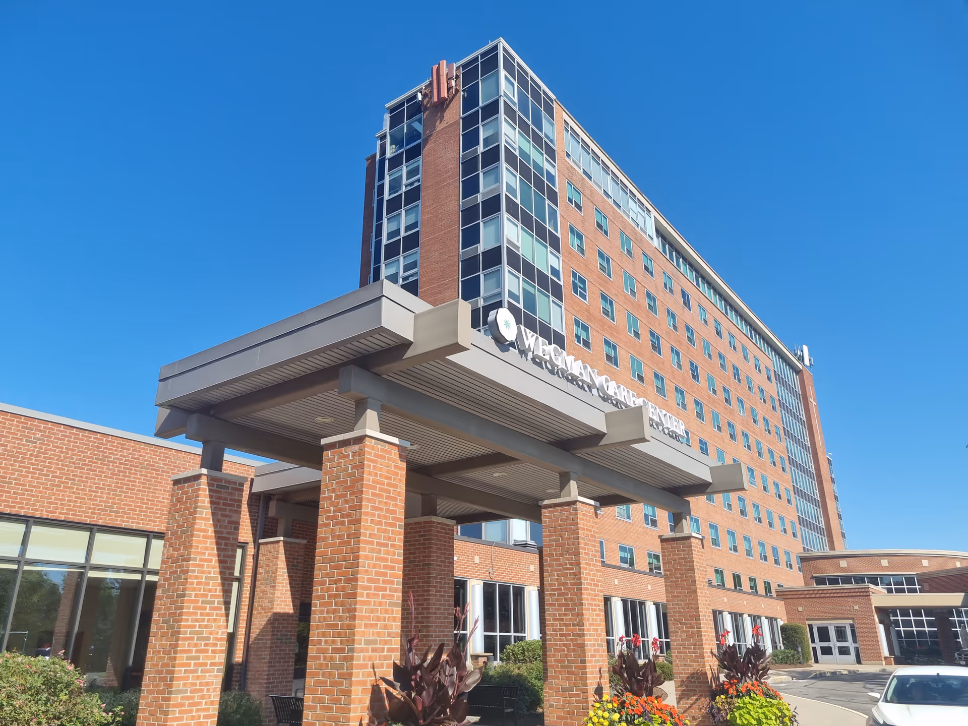 Tall brick senior living building with a covered entrance and landscaping