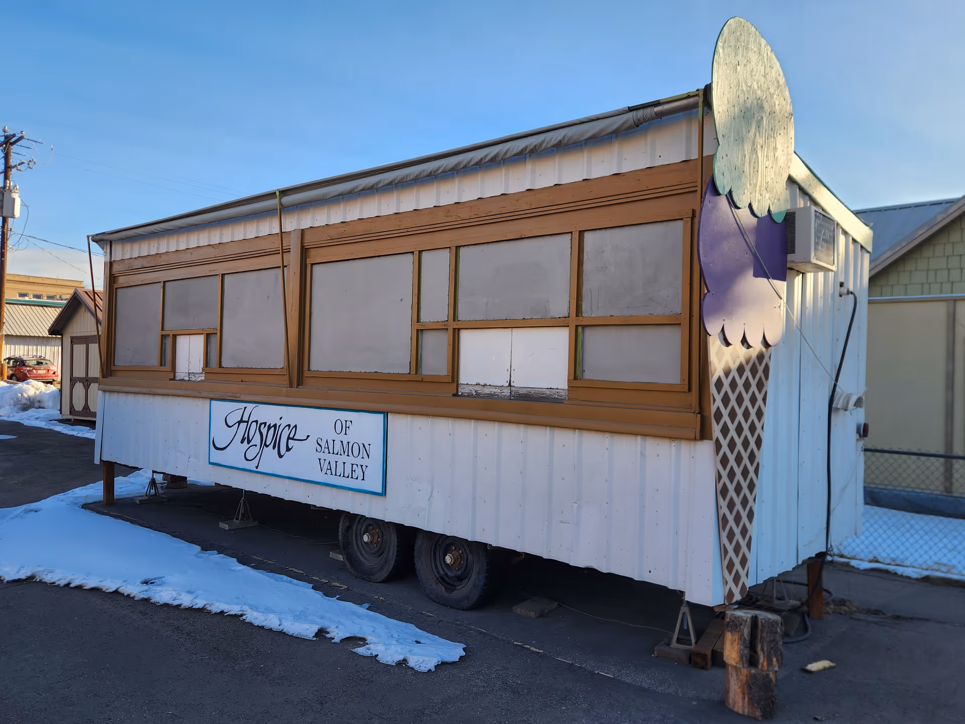 A mobile hospice trailer labeled Hospice of Salmon Valley sits on a snowy lot.