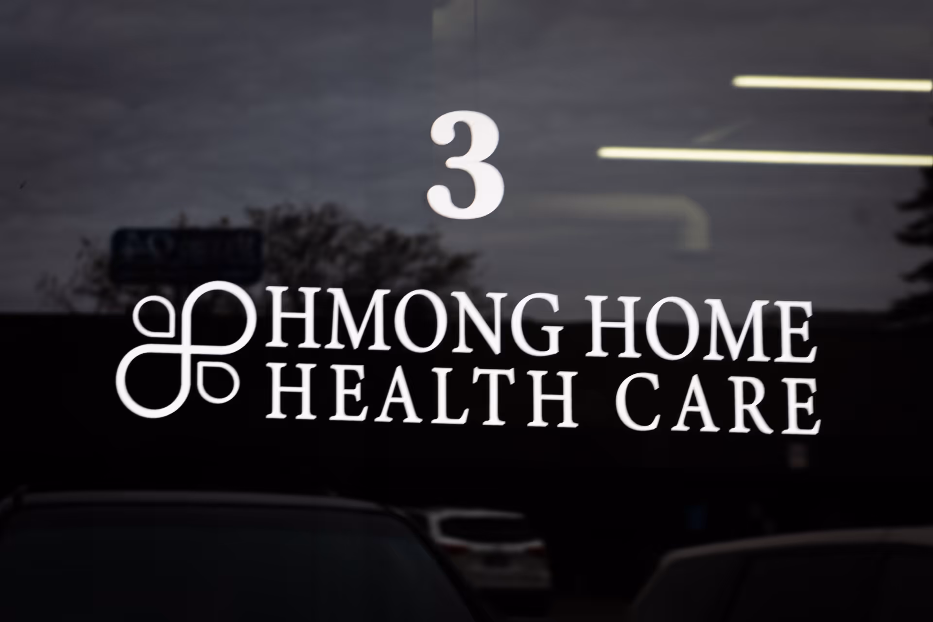 Glass storefront displays Hmong Home Health Care with a large number 3 and reflections.