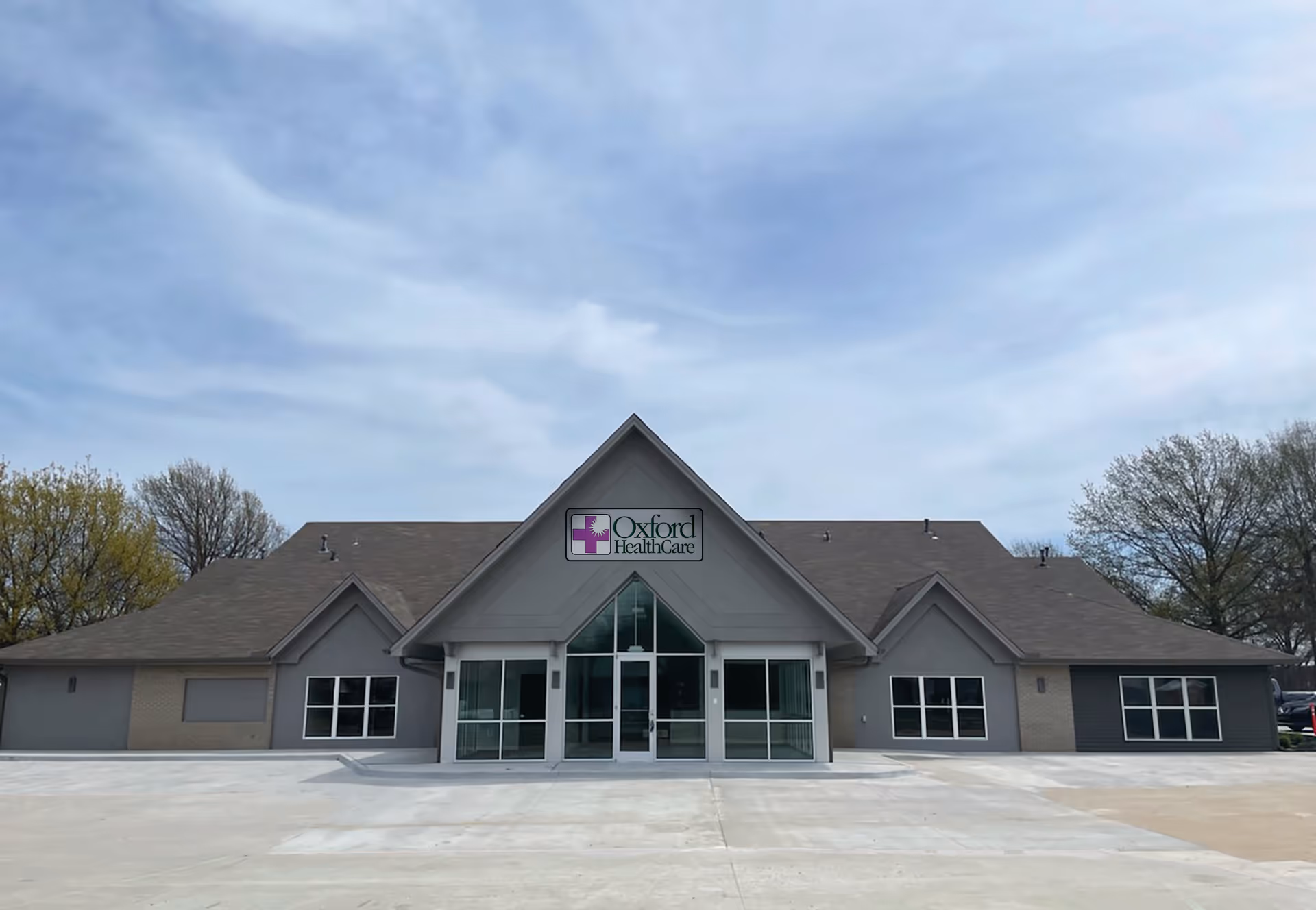 Exterior view of Oxford HealthCare building with a glass entrance and peaked roof.