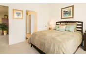 Bedroom in a senior care facility with a bed, lamps, and framed art.