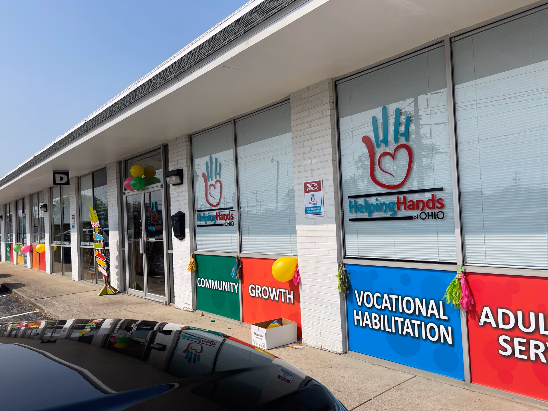 Exterior view of Helping Hands of Ohio facility storefront with colorful signs and balloons.